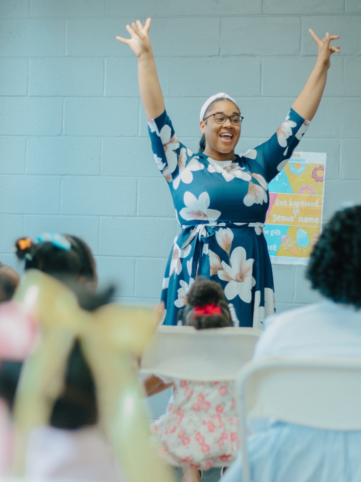 A Greater Kids teacher with her arms raised leading class